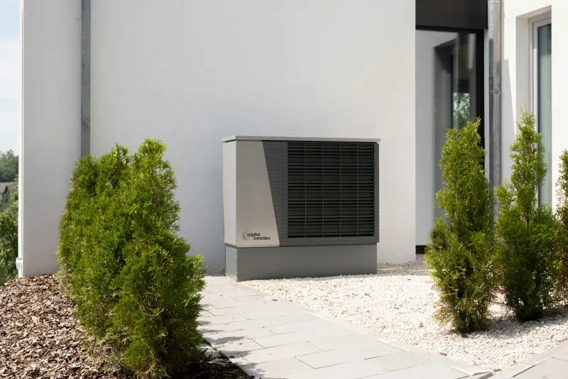 Een warmtepomp-buitenunit tegen een gevel